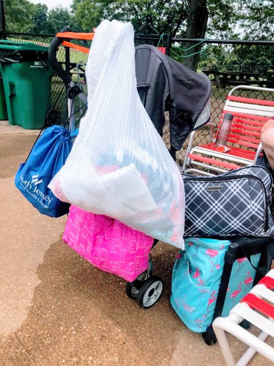 A stroller with several bags on it at the pool