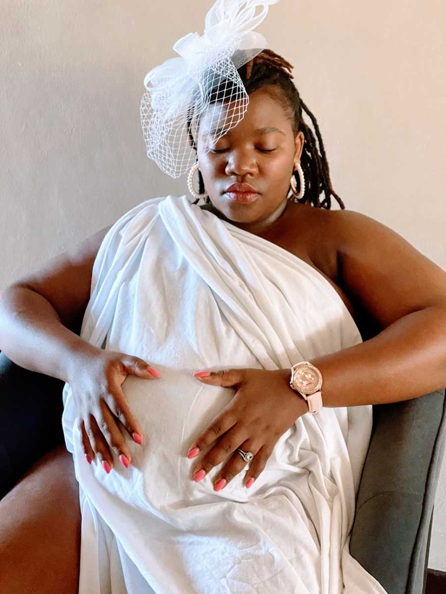 A pregnant woman holds her hands over her stomach