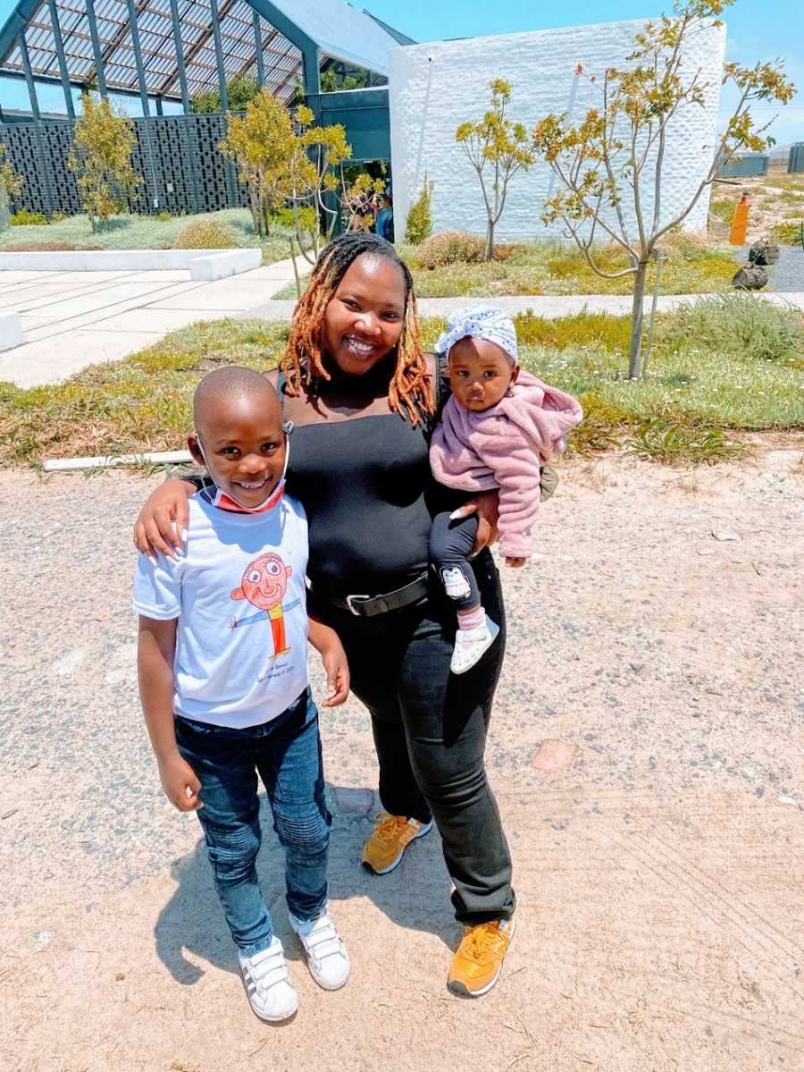 A woman stands with her son and young daughter