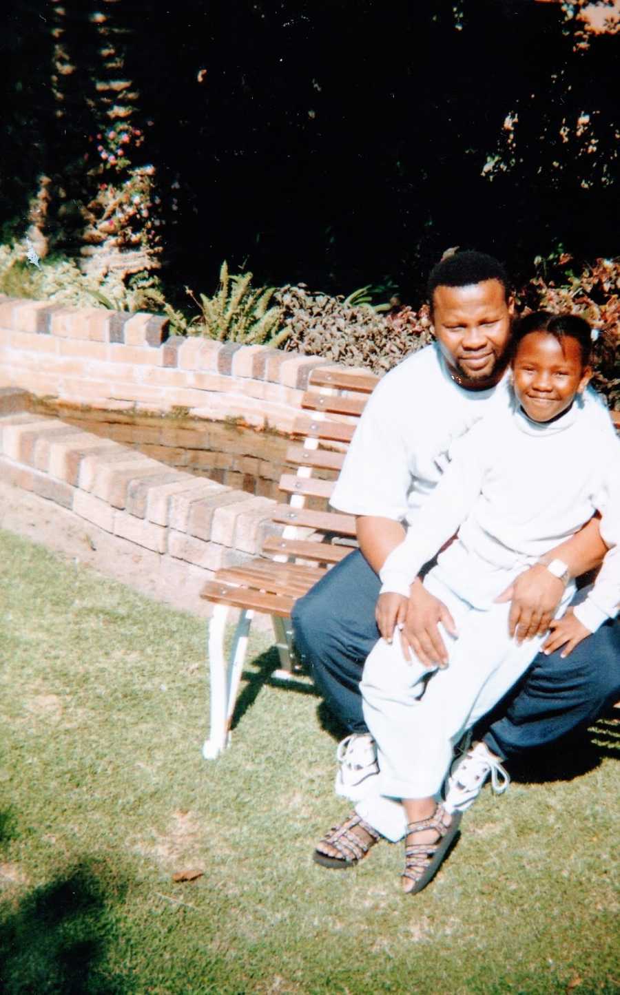 A young girl dressed in white sits with her father