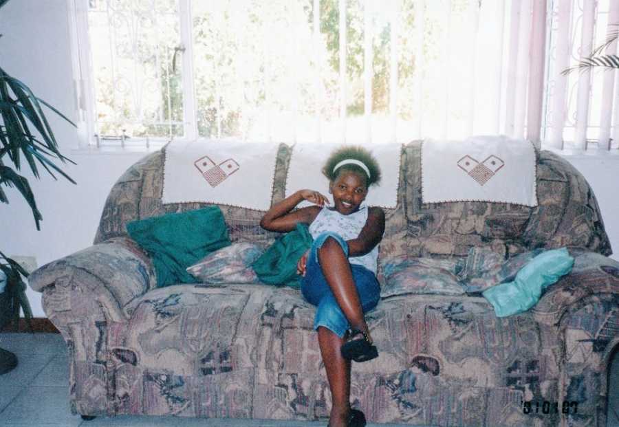 A young girl sits alone on a floral couch