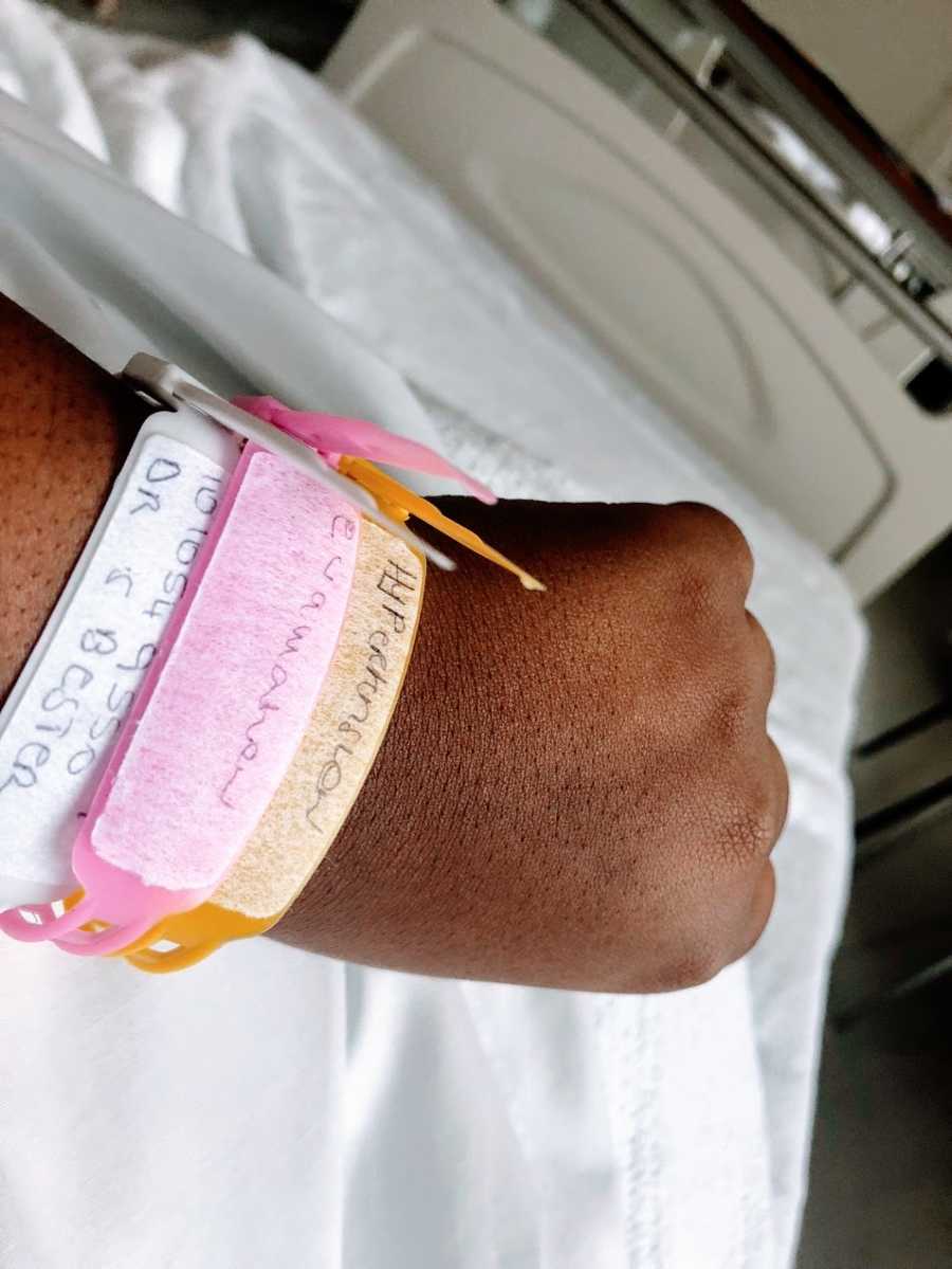 A woman in the hospital displays her hospital bracelets on her wrist