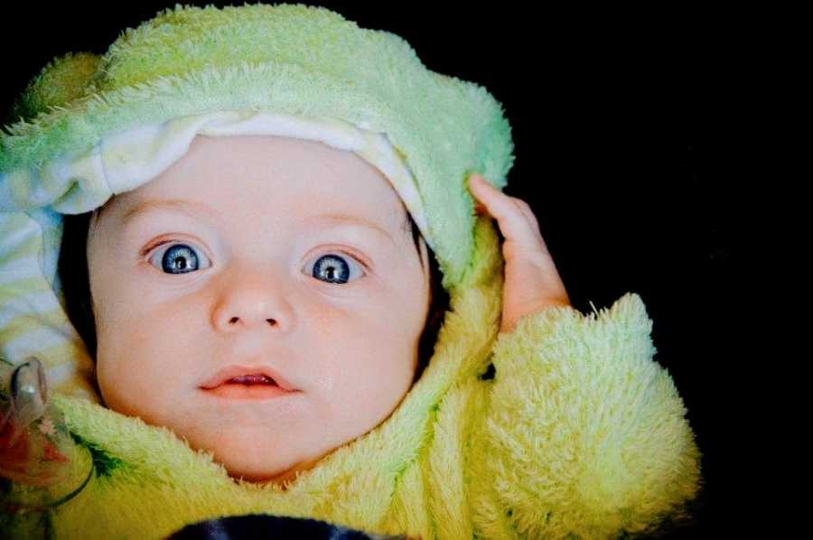 A young boy dressed in a green hooded outfit