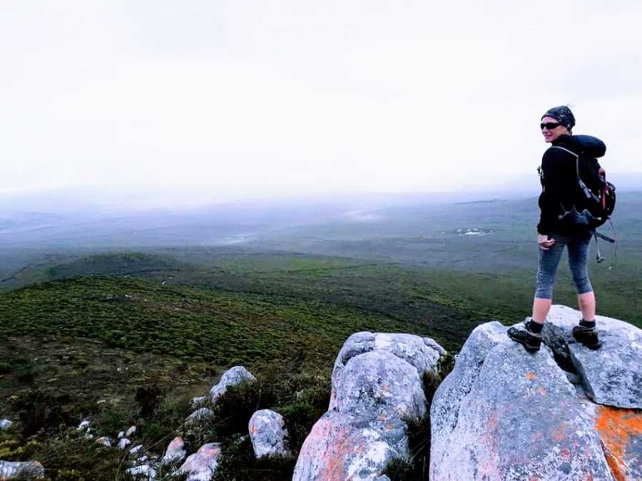 A mother stands on a rock overlooking a field