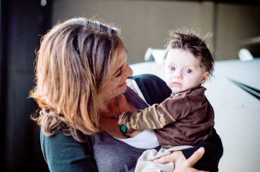 A woman holds up her toddler son