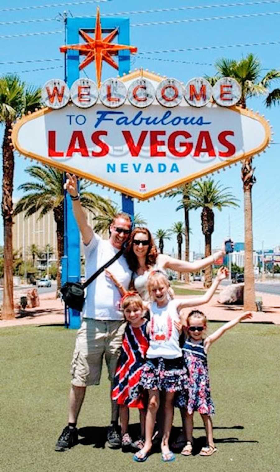 A family stand together outside of a Vegas sign