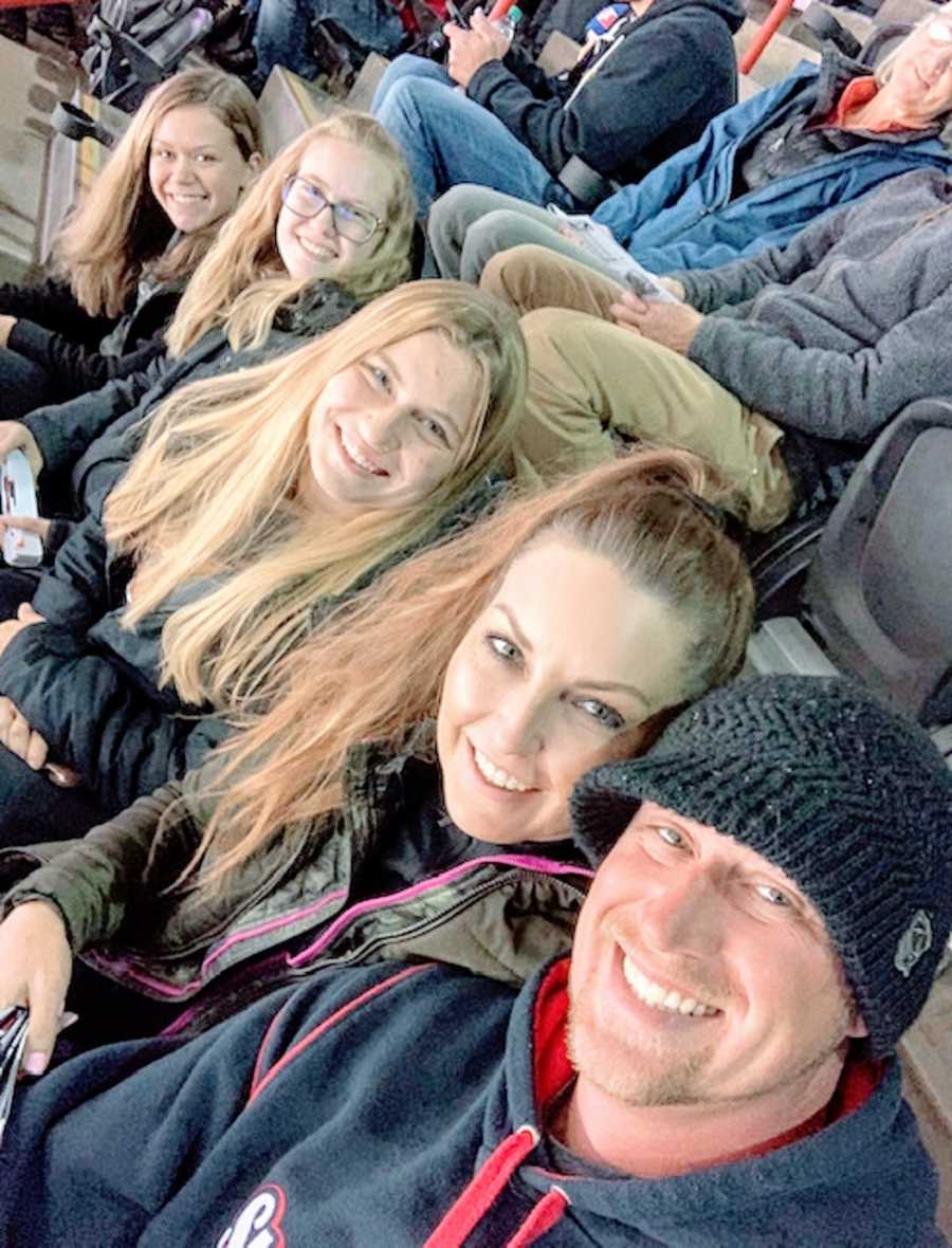 A family of five sit together at a sporting event