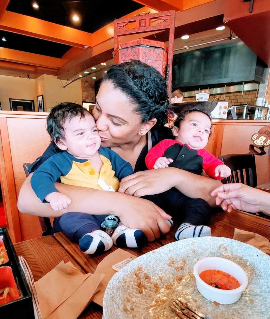 A mother holds her baby twins in a restaurant