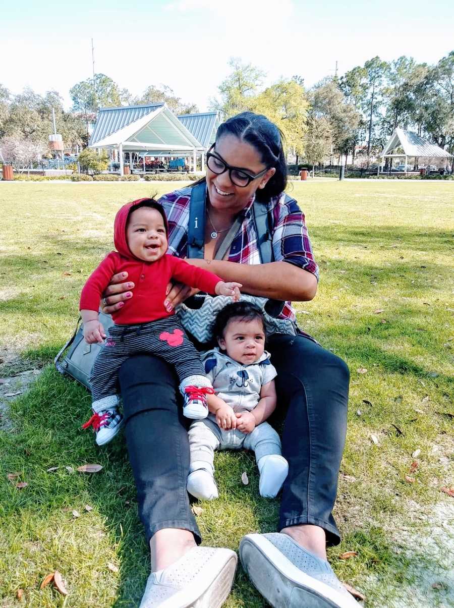 A woman sits in the park with her twin sons