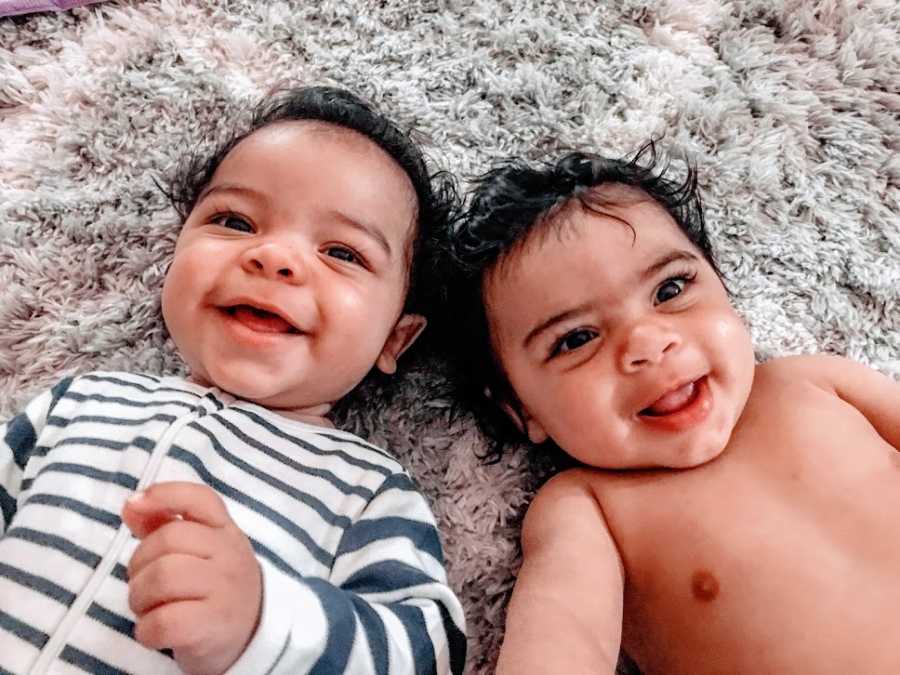 Twin brothers lie on their backs on the ground