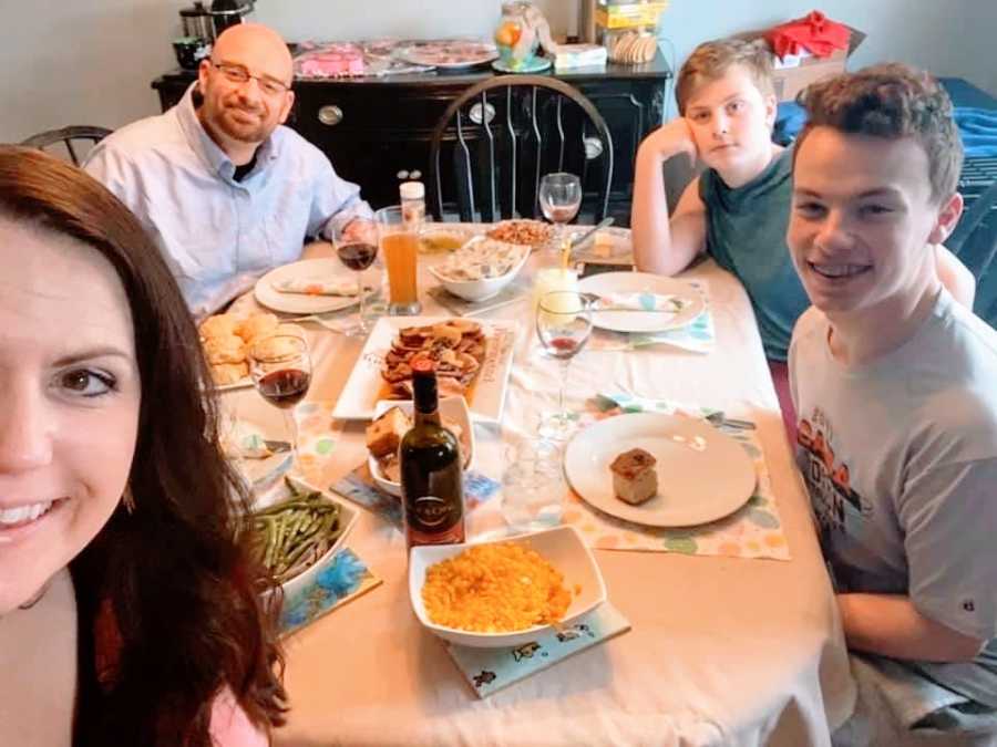 A family of four sit together around a dinner table