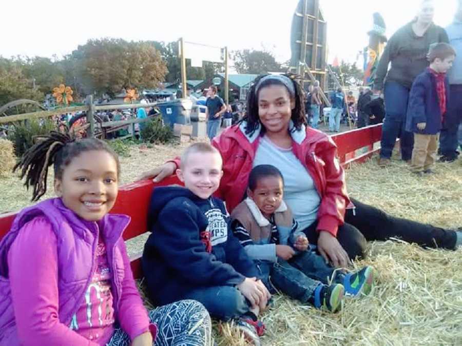 A mother with her three older children sitting in hay