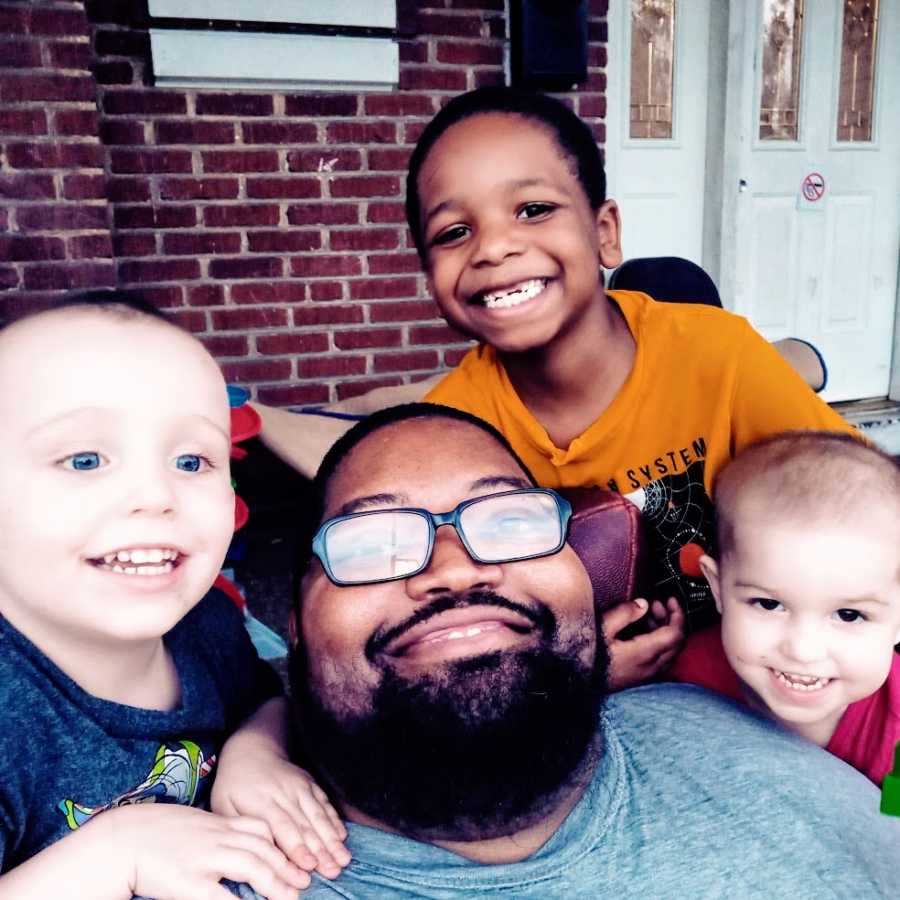 A father sits with his three sons on the front porch