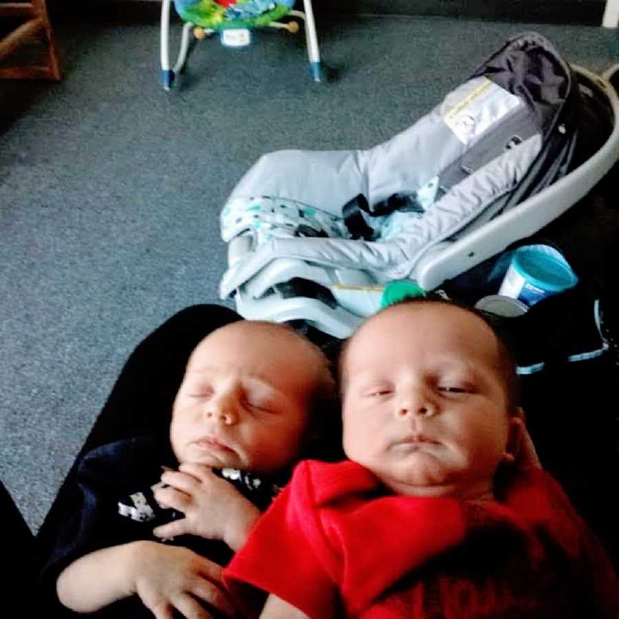 Twin baby boys lie on their backs sleeping