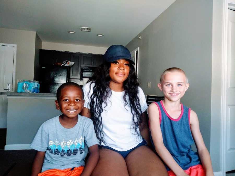 An older girl sits with her two younger brothers