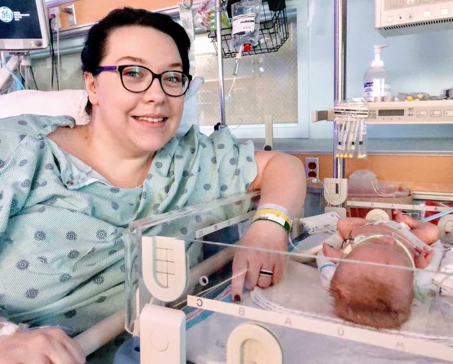 A woman sits next to her baby in the hospital