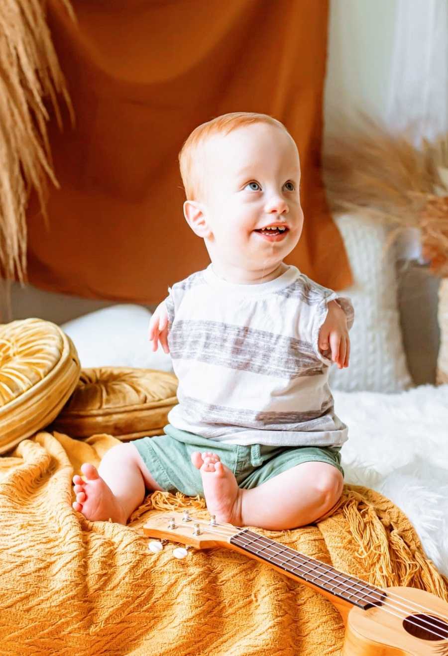 A boy with no arms wearing a grey striped shirt