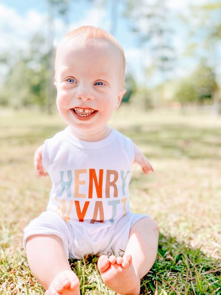 A boy with no arms smiling in a park