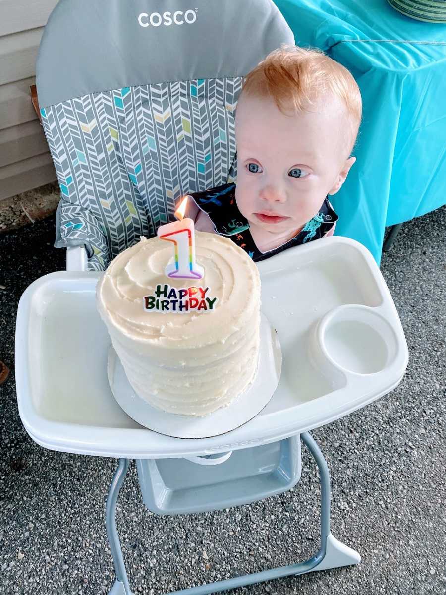 A little boy with no arms stares at his birthday cake