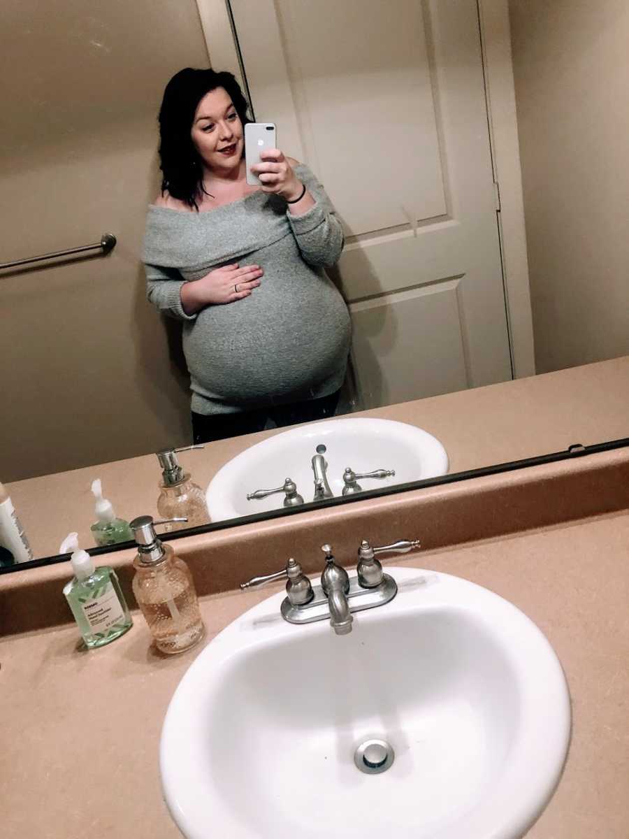 A pregnant woman takes a photo in the bathroom mirror