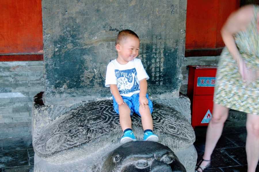 A little boy sits on top of a stone structure