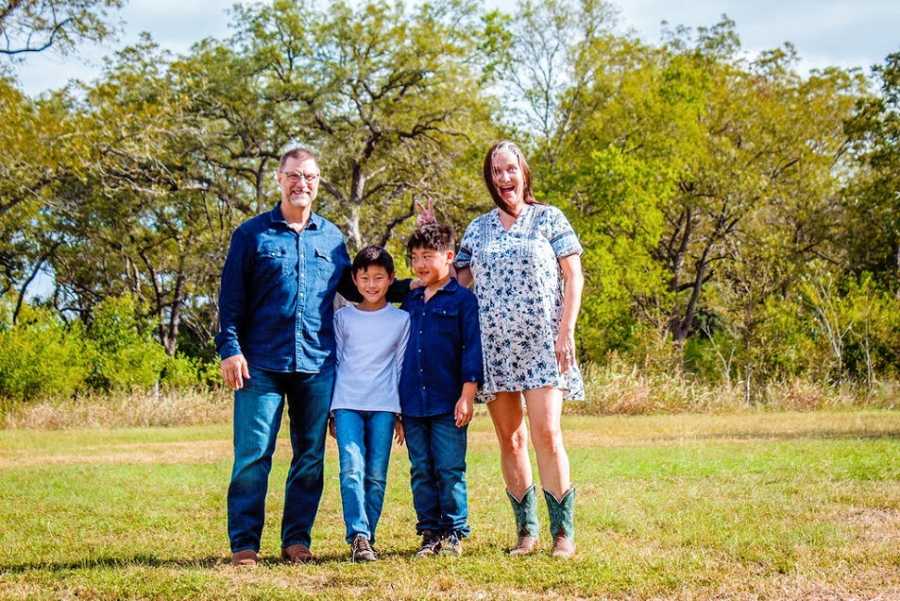 Parents stand in a field with their two adopted sons