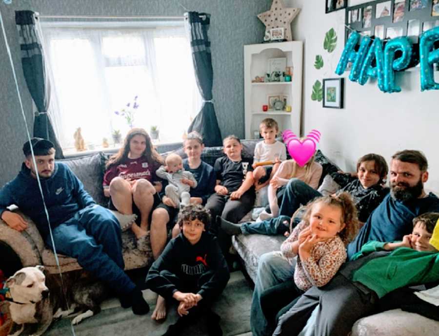 A family with eleven kids sits on a sofa