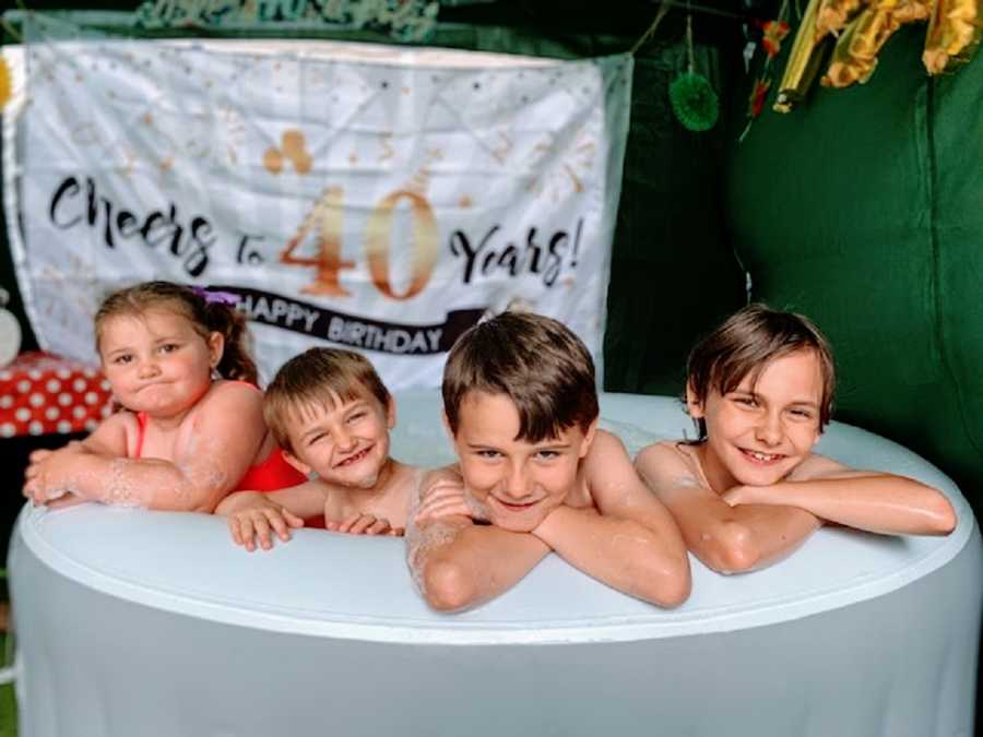 Four children sit in a bathtub