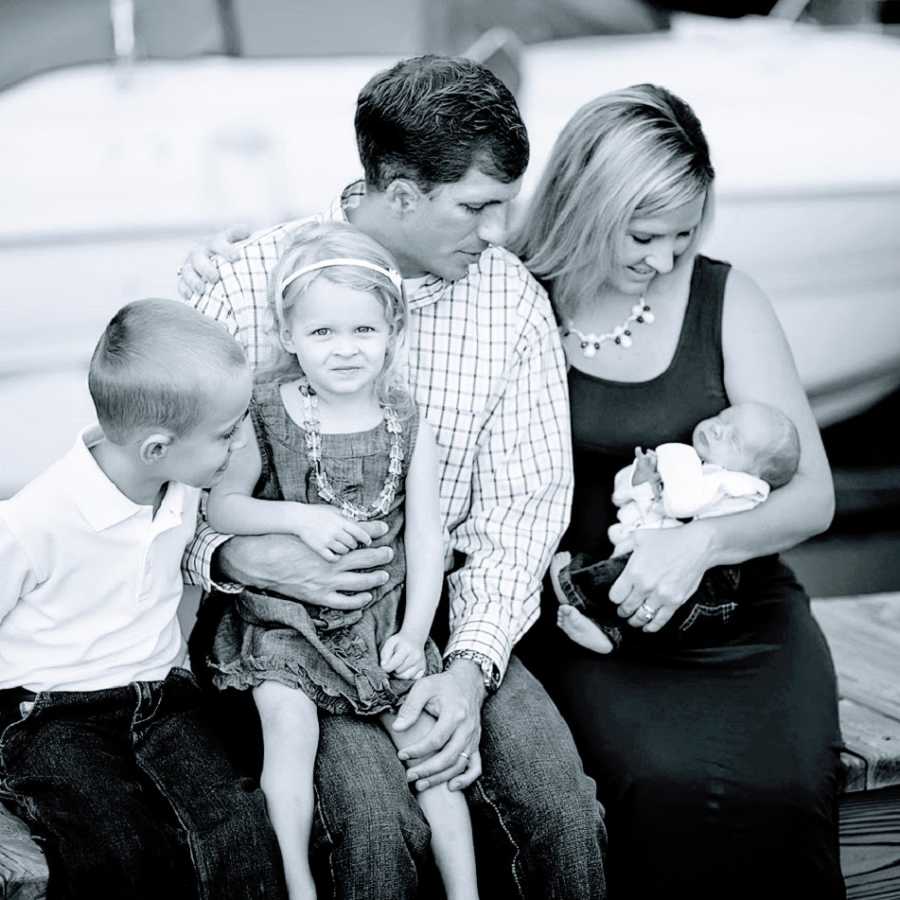 Parents sit with their three young children