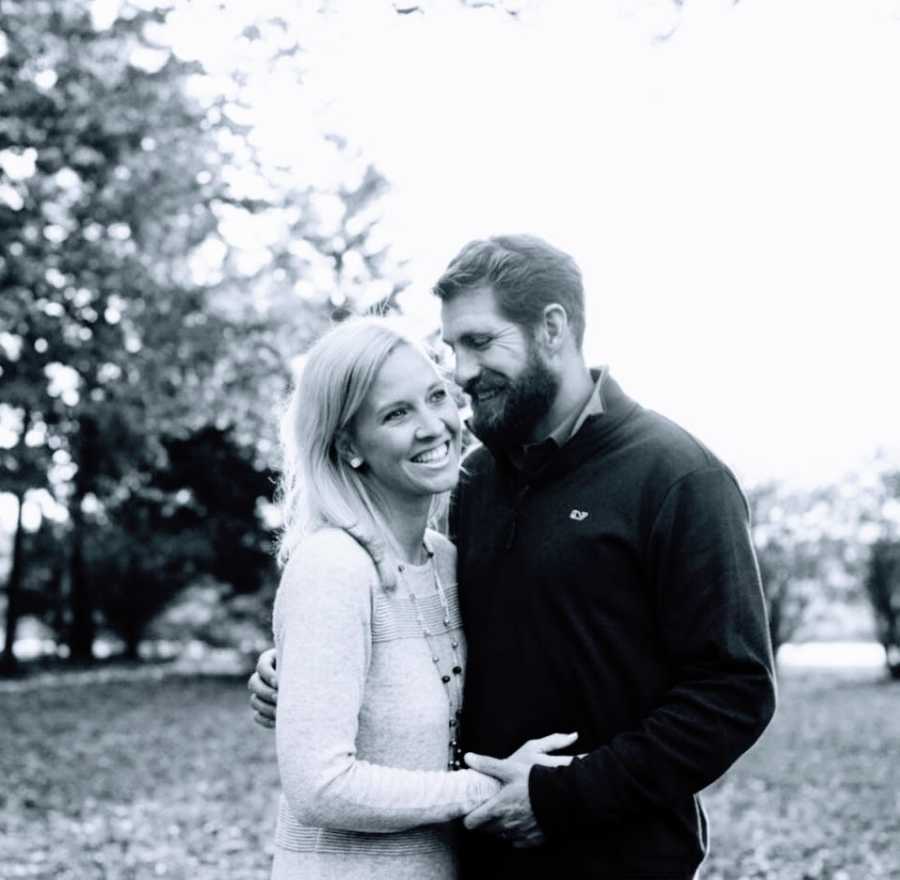 A woman stands with her husband outside