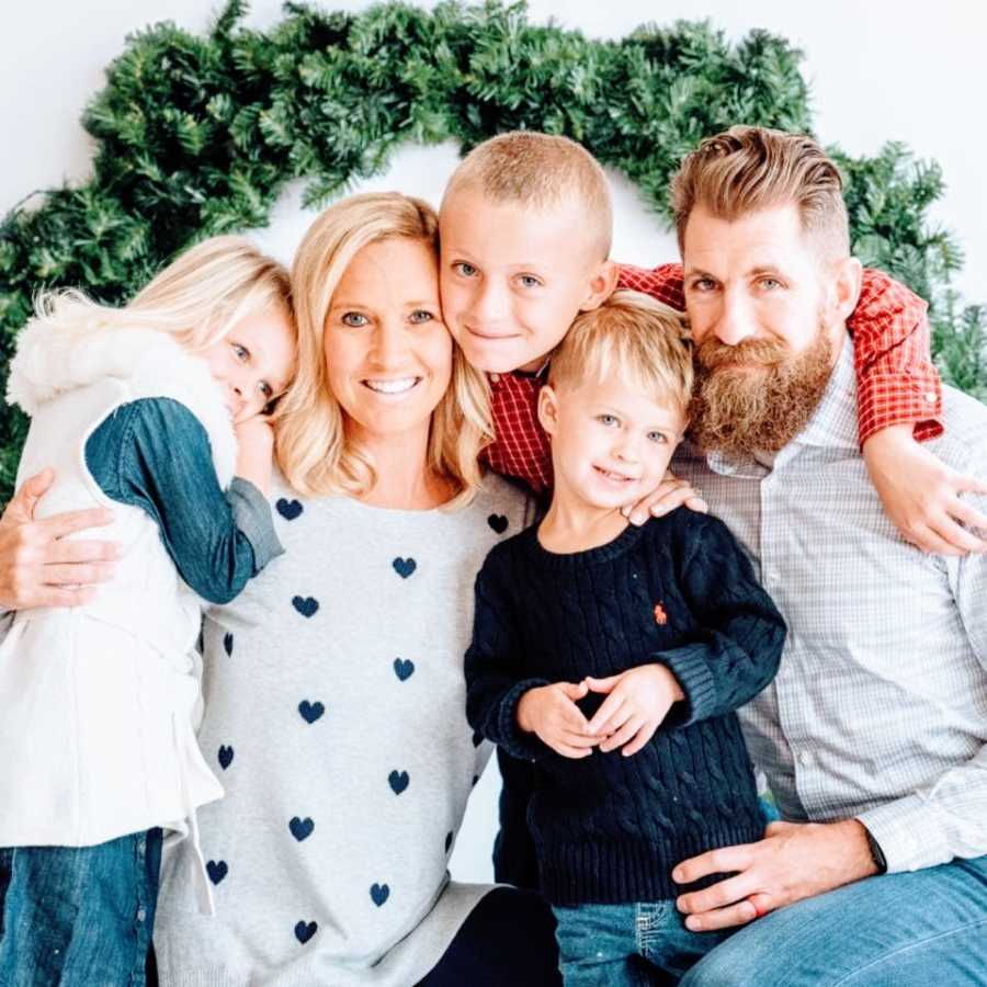 A family with three children sit in front of a wreath