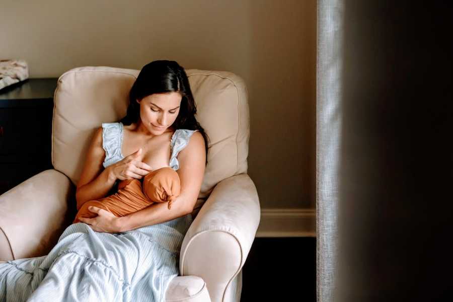 A woman holds her young baby sitting in an armchair