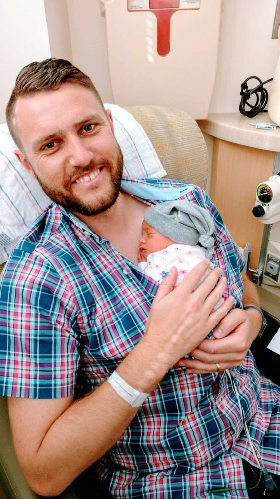 A father holds his newborn baby girl in the hospital