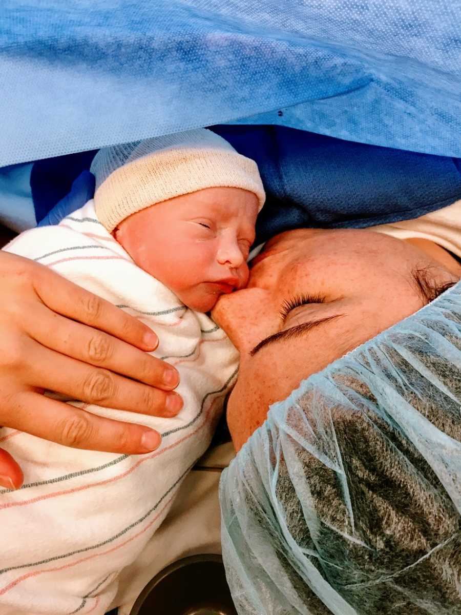 A mother kisses her newborn baby girl