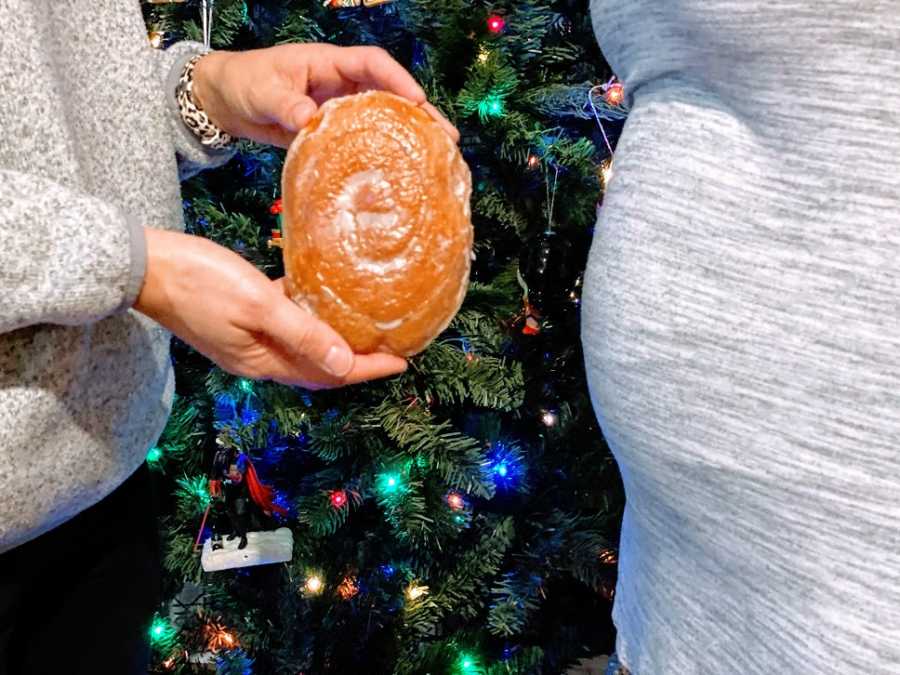 A woman holds a bun next to a pregnant woman's stomach