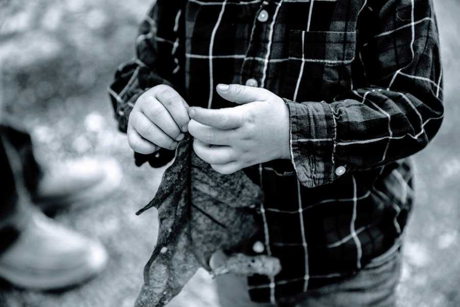 A foster child wearing a plaid shirt picks at his fingernails