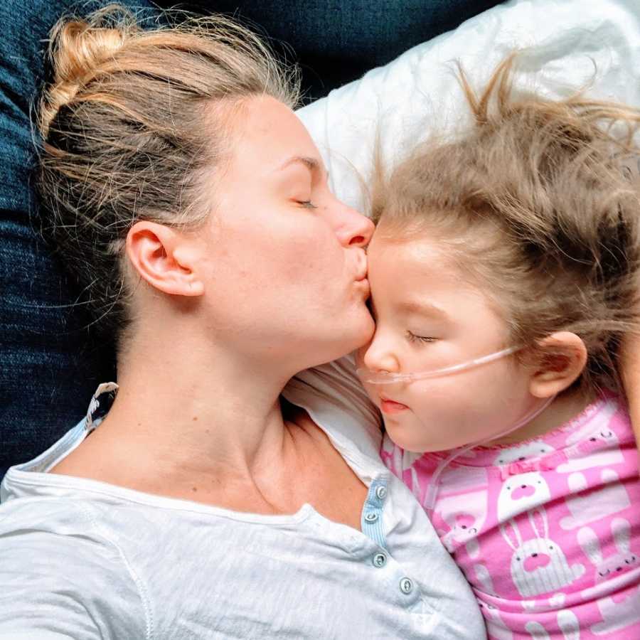 A mother kisses her daughter on the forehead