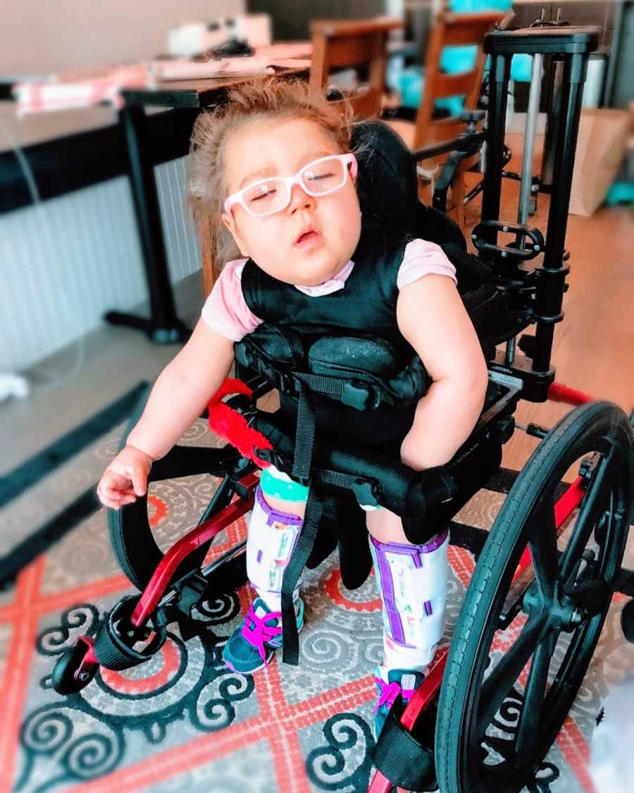 A little girl with epilepsy stands in a wheelchair