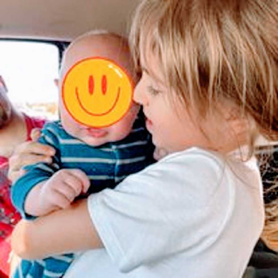 A little girl holds her newborn foster brother