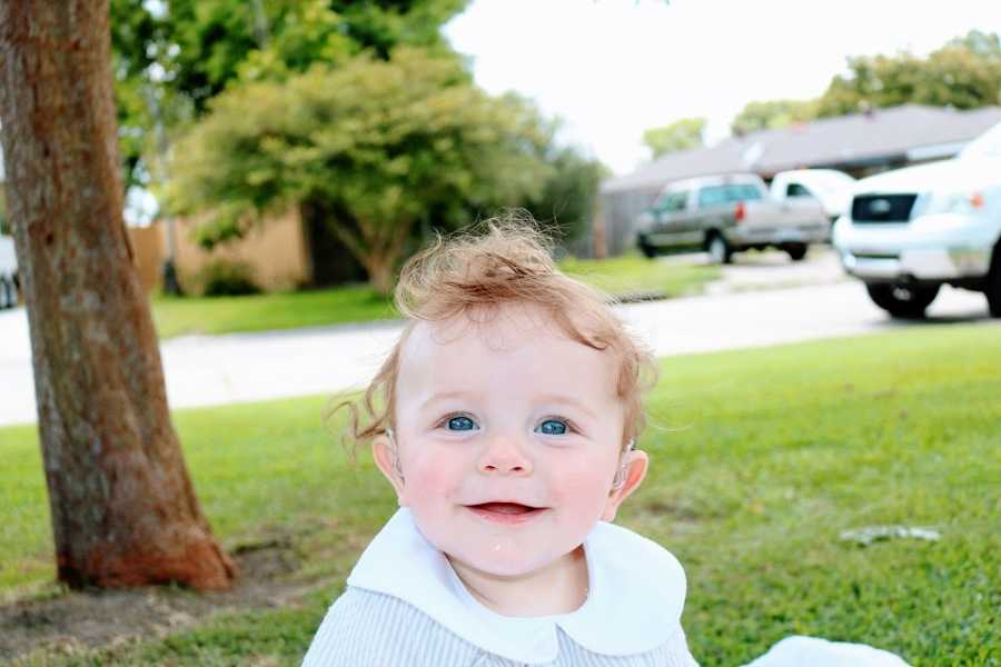 A little boy sitting outside wearing a white shirt