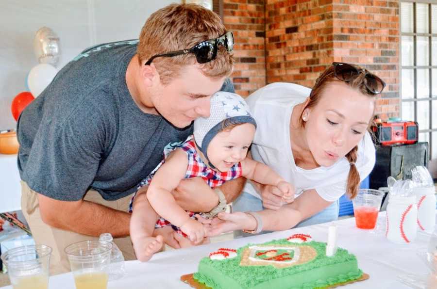 A little boy and his parents blowing out birthday candles