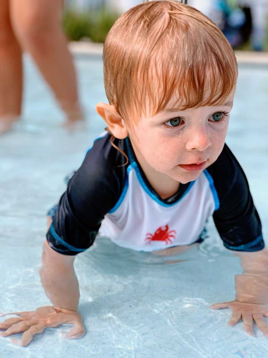 A little boy sits in a shallow pool