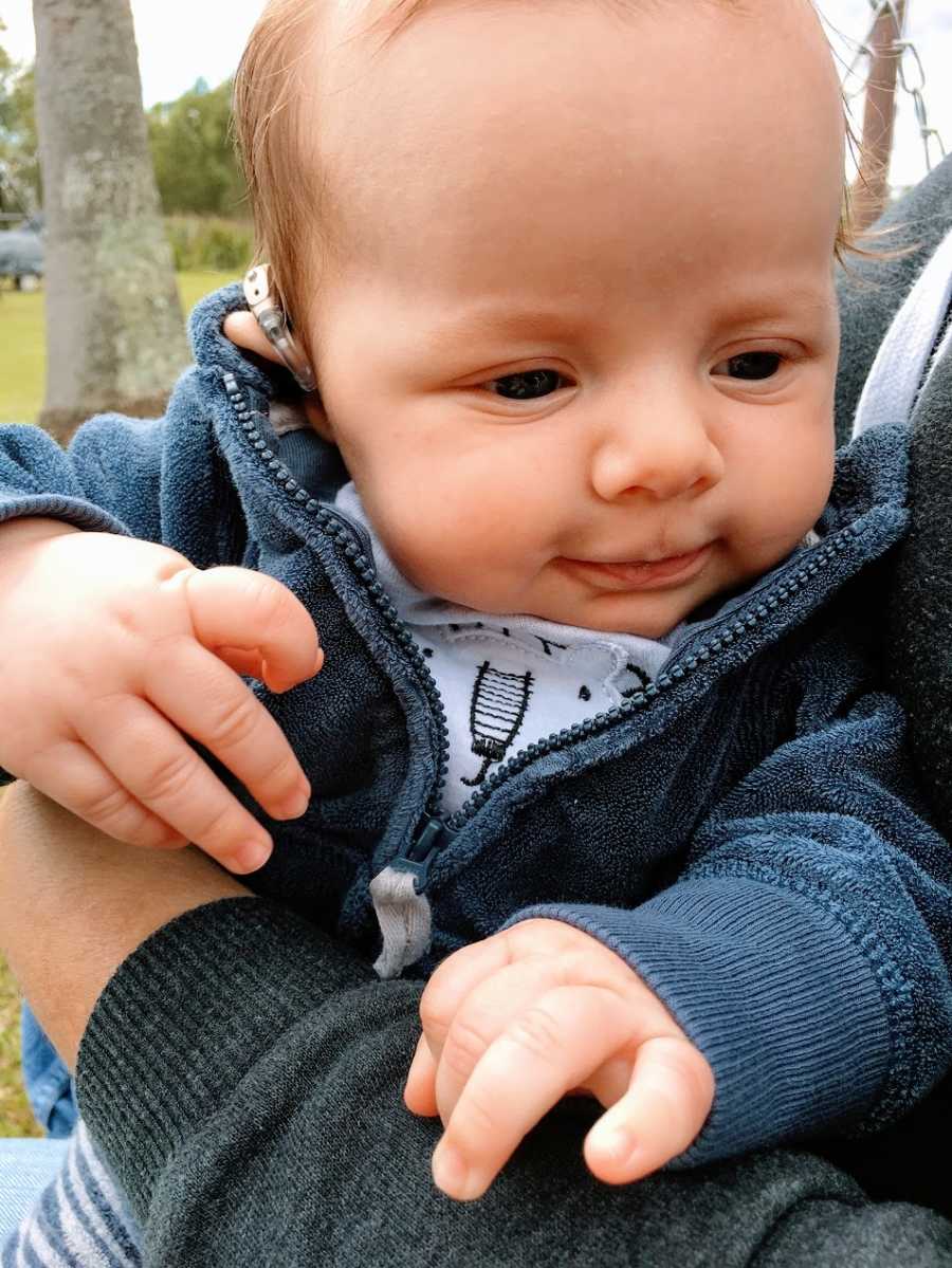 A little boy wearing hearing aids and a sweatshirt