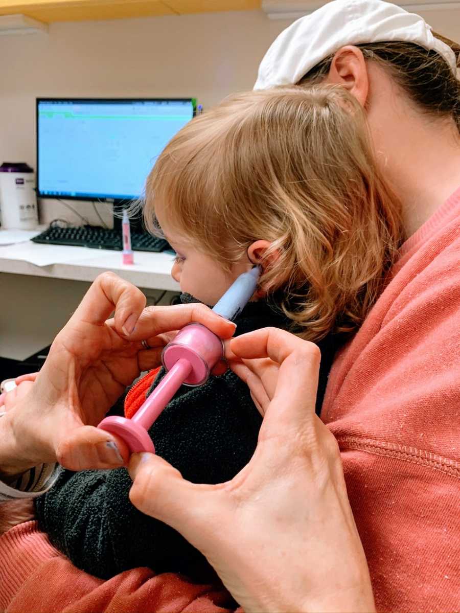 A little boy sitting on his parent's lap at a doctor's appointment