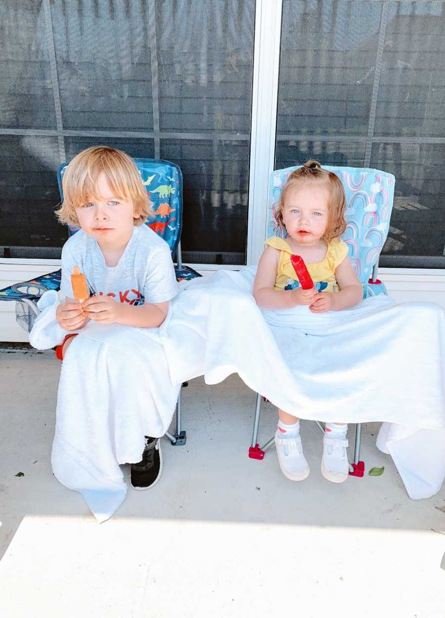 A boy and his sister sit in chairs holding popsicles