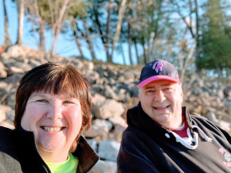 A woman and her husband sit together on a beach