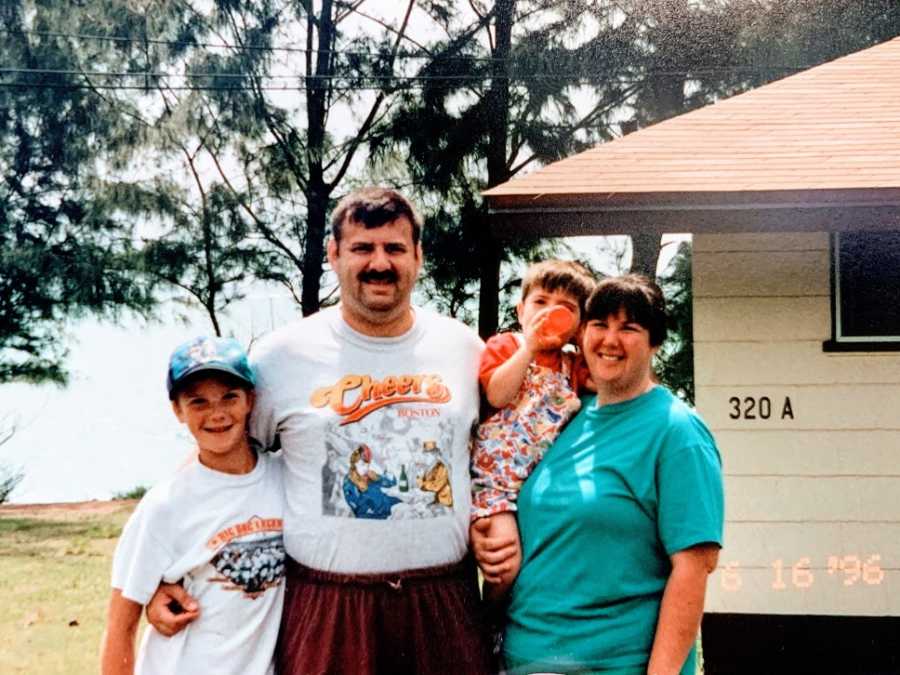 A family of four stand together outside