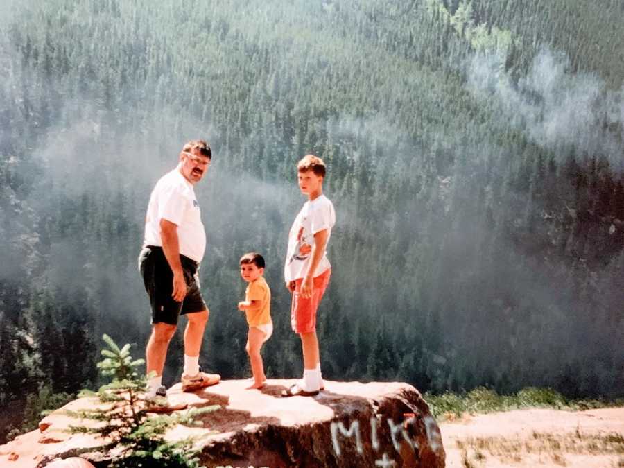A man stands with his two young sons overlooking a cliff