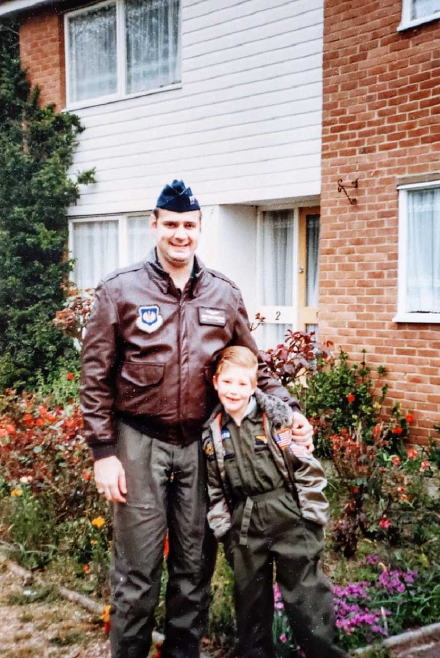 A man in a military uniform stands with a young boy outside