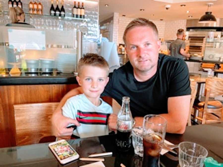 A man and his son sit in a booth at a restaurant